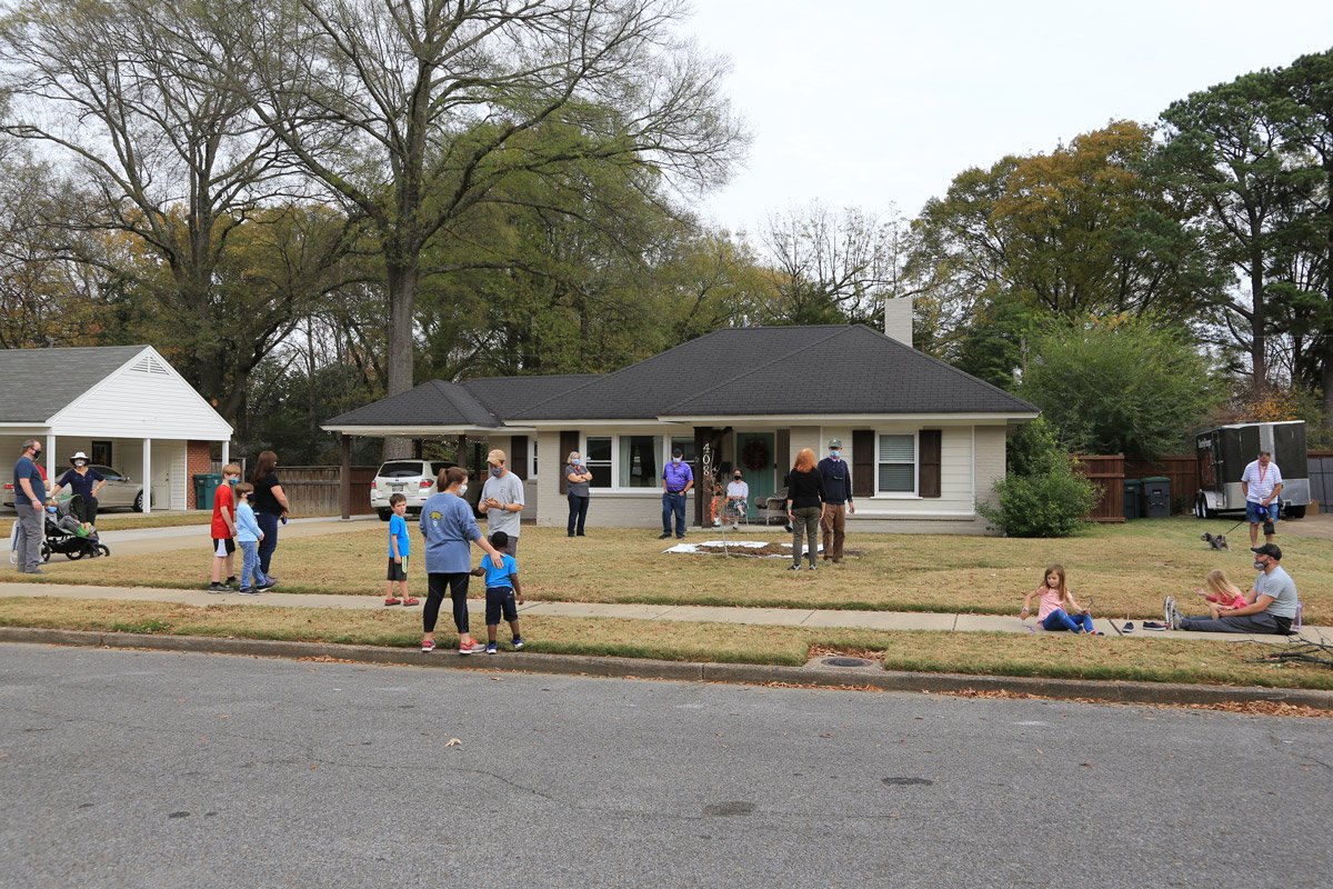 Neighbors, including families with children and dogs, gathered at social distances