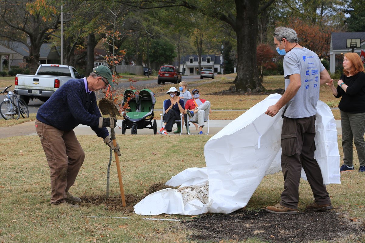 Mark Follis tamps down the soil as arborist Ted McLaughlin assists